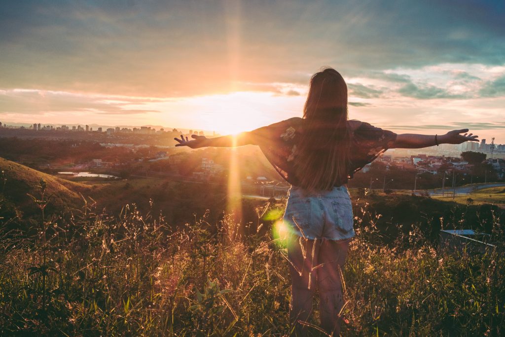 vrouw armen gespreid met zon